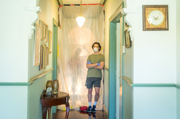 Matthew Thomas isolating at one end of his parents house cut off from the rest of his family by two plastic sheet dividers.