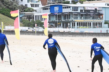 Surfers emerge from the water on Bondi Beach on Friday with North Bondi RSL Club in the background.