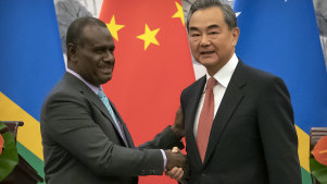 Solomon Islands Foreign Minister Jeremiah Manele, left, and Chinese Foreign Minister Wang Yi shake hands during a ceremony to mark the establishment of diplomatic relations between Solomon Islands and China.