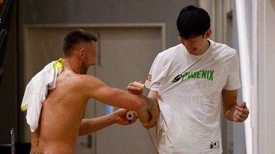 Phoenix teammate Mitch Creek turns physio for Zhou Qi before an NBL Blitz match.