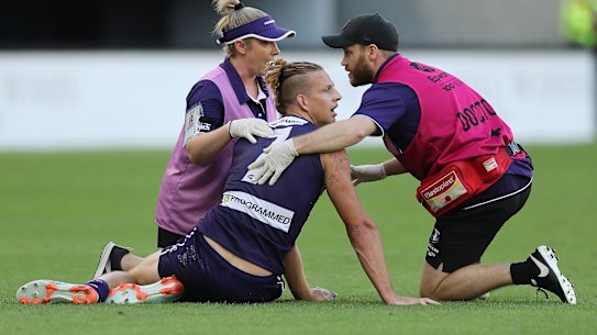 Nat Fyfe of the Dockers receives attention after a heavy knock from Sam Reid.