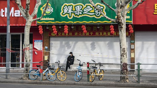 A security guard sits in front of closed stores in a locked down Shanghai neighbourhood. 