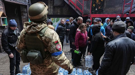 Ukrainian servicemen distribute water to people in Mariupol.