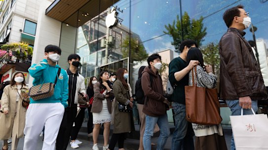 People wearing protective masks wait in line outside the Apple store in the Gangnam district of Seoul.