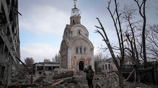 A Ukrainian serviceman takes a photograph of a damaged church after shelling in a residential district in Mariupol, Ukraine.