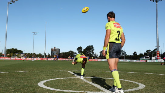 Umpires practice the art of the centre bounce.