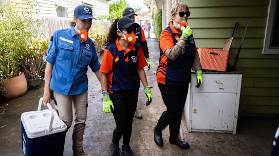 A Disaster Relief Australia official (in blue) attends a Maribyrnong home with community volunteers.