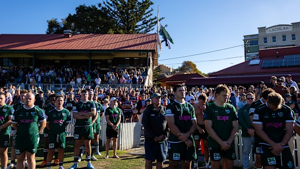  People stand for a moment of silence as Peter Meagher, a Bondi Beach mass shooting victim, is farewelled by Randwick at the Coogee Oval in Coogee before the Shute Shield game between Randwick and Eastern Suburbs