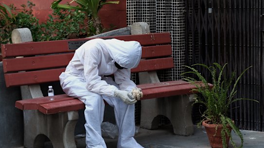 A relative of a Covid-19 fatality wears personal protective equipment (PPE) while sitting on a bench outside a cremation hall at the Nigambodh Ghat crematorium in New Delhi India, on Monday, April 19, 2021.