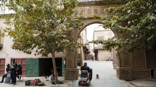 Police officers stand guard on a street as a motorist drives past in Kashgar, Xinjiang autonomous region, China.