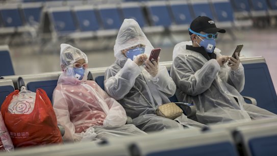 Travellers at a train station in Shanghai wear gear to try to protect themselves from coronavirus.