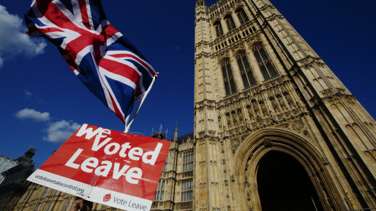 A Pro-Brexit demonstrator waves a flags while protesting outside the Houses of Parliament in London.