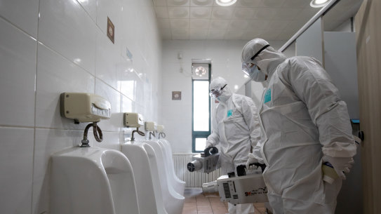 Workers disinfect a toiliet at a SOuth Korean bus depot.