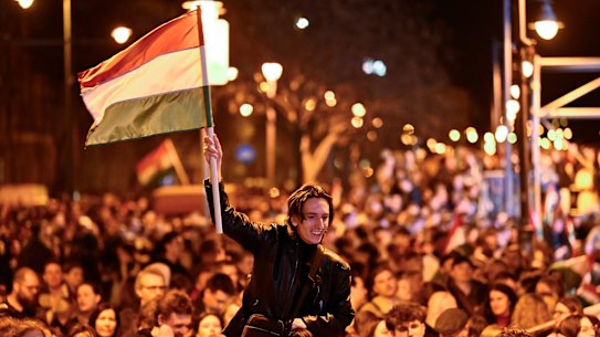 Um homem agita uma bandeira húngara enquanto comemora nas ruas após o anúncio dos resultados parciais.