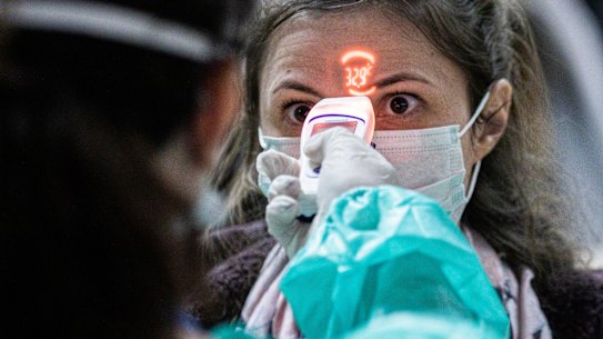 A health worker screens the temperature of an airline passenger arriving from Italy at Debrecen International Airport in Debrecen, Hungary