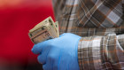 A vendor wearing protective gloves holds cash at a farmers' market in San Francisco.