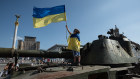 A boy holds a Ukrainian flag atop a Russian tank displayed in Kyiv ahead of Independence Day.