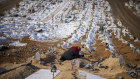 A woman cries over the graves of her son and her daughter, killed during the earthquake at Sehir cemetery in Malatya, Turkey.