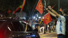 Supporters of the opposition Workers' Party wave flags at passing traffic in celebration as results of sample counts are announced on Saturday.