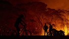 Residents look on as flames burn through bush on January 04, 2020 in Lake Tabourie, Australia. 