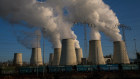 Electrical power lines hang from a transmission pylon beside vapor rising from cooling towers at the Jaenschwalde lignite-fired power plant