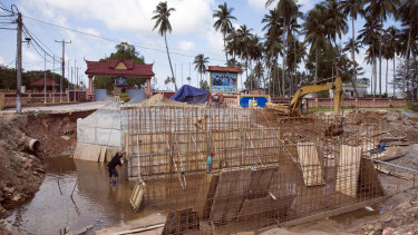 Workers labour on an under construction road outside Ream Naval Base in Sihanoukville, Cambodia.