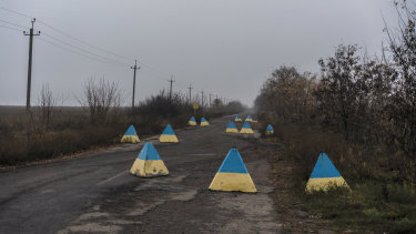 Concrete barriers in the yellow and blue of the Ukrainian flag, near a military checkpoint outside Hranitne, Ukraine.