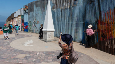 A visitor takes a photograph near a section of the US and Mexico border wall on the beach in Tijuana, Mexico.