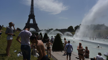 Parisians and tourists cool off in the Trocadero esplanade fountain near the Eiffel Tower in Paris on Friday. 
