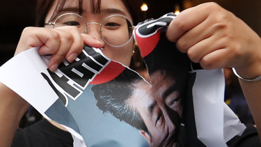 A South Korean protester in Seoul on Friday tears an image of Japanese Prime Minister Shinzo Abe. Japan announced it would restrict exports to South Korea amid a spat that puts jobs at risk jobs and threatens the global supply of microchips and smartphone displays.