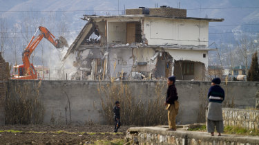 A police commando stands guard as authorities use heavy machinery to demolish Osama bin Laden’s compound in Abbottabad in 2012.