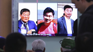 People watch a TV news report on screen displaying portraits of three Americans, from left, Kim Dong-chul, Tony Kim and Kim Hak-song, detained in North Korea.