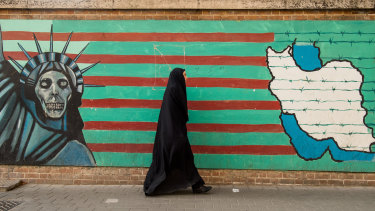 A woman wearing a chador walks past an anti-American wall mural outside the former US embassy in Tehran, Iran.