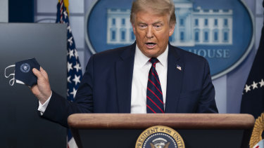 President Donald Trump holds a mask as he speaks during a news conference at the White House.