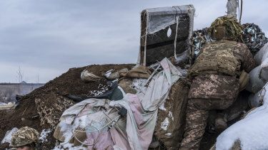 A Ukrainian soldier, uses a small hand-held periscope to view the positions of Russian-backed troops from a small bunker.