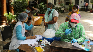 Health workers take blood samples from residents in New Delhi, India.