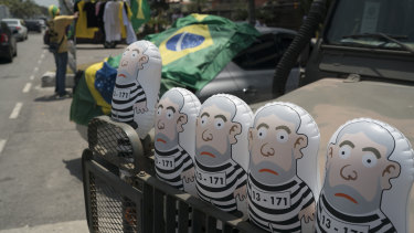 Inflatable dolls of Brazil's jailed former Brazilian president Luiz Inacio Lula da Silva, wearing prisoner garb, are displayed on the grill of a jeep in front of the entrance of the condominium where presidential candidate Jair Bolsonaro lives.