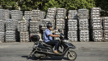 Bundles of aluminum ingots sitting stacked on the side of a road near a China National Materials Storage and Transportation Corp. stockyard.