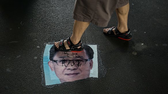 A demonstrator walks over a photo of Junius Kwan-yiu Ho, a Hong Kong legislator, during a protest in the Yuen Long district.