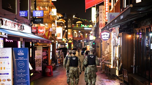 US Army military police patrol the street at night in the Itaewon area of Seoul, South Korea.