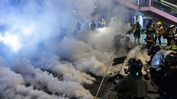 Riot police walk toward a cloud of tear gas as they attempt to disperse demonstrators during a protest in the Sheung Wan district of Hong Kong.