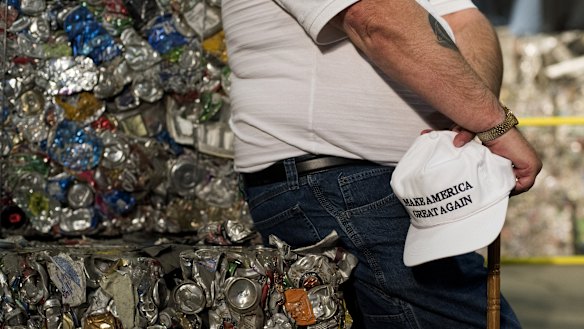 An attendee sits on a stack of crushed aluminium cans before the start of a campaign event with Donald Trump.