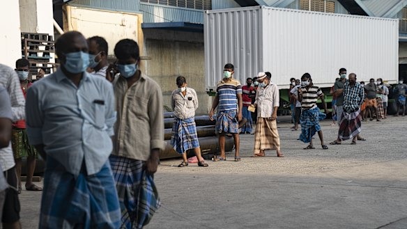 Migrant workers in Singapore line up on April 17 to receive SIM card top ups from volunteers.