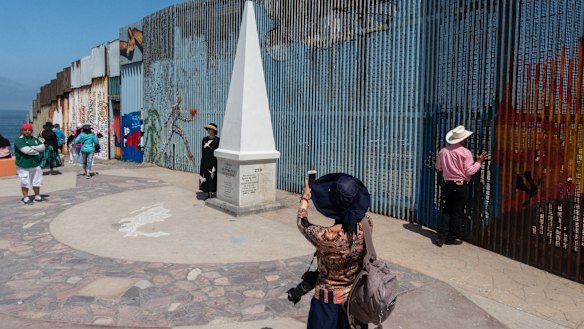 A visitor takes a photograph near a section of the US and Mexico border wall on the beach in Tijuana, Mexico.