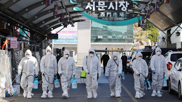 Workers spray disinfectant as a precaution against the COVID-19 at a local market in Daegu, as the country raises the alert level.