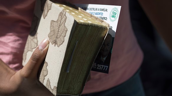 A woman holds her Bible, and an electoral leaflet promoting two candidates that was distributed at the Assembly of God Victory in Christ Church in Rio de Janeiro, Brazil.