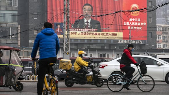 My way or the highway: Beijing commuters travel past a screen broadcasting Chinese Premier Li Keqiang speaking at the National People’s Congress. 