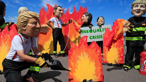 A man wearing a mask President Donald Trump, front left, is joined by other 'world leaders' during a protest ahead of the G-7 summit in Biarritz, France.