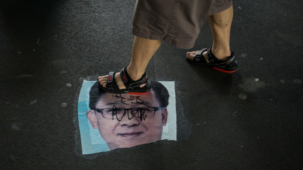 A demonstrator walks over a photo of Junius Kwan-yiu Ho, a Hong Kong legislator, during a protest in the Yuen Long district.