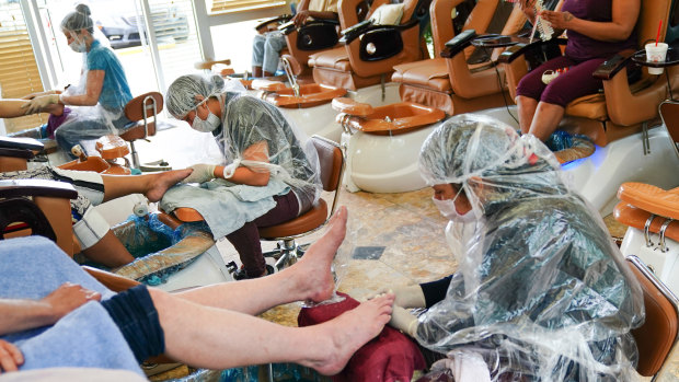 Workers wearing protective gear give customers pedicures at a nail salon in Atlanta, Georgia.
